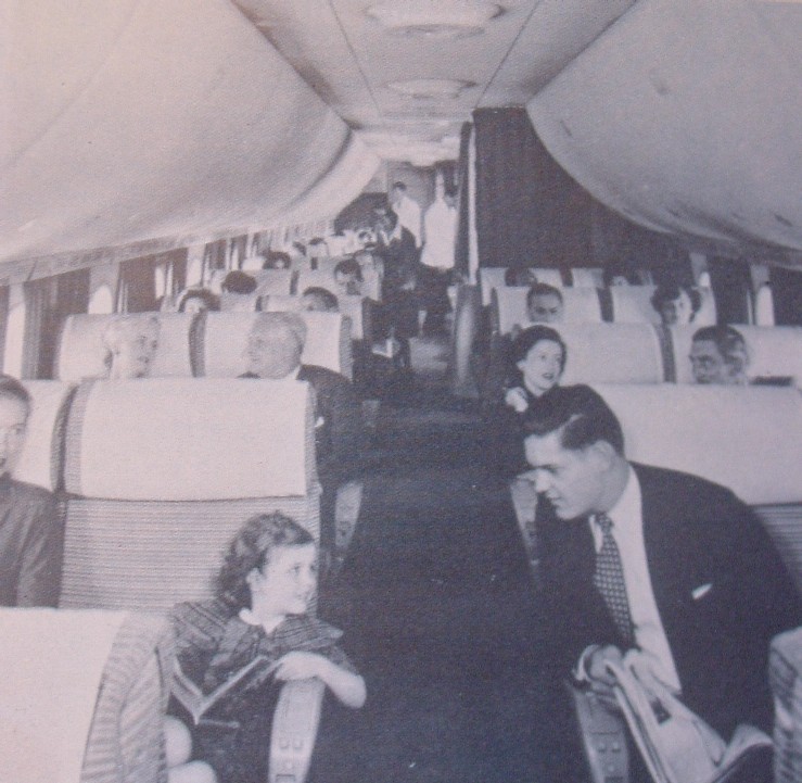 1950s Young lady & gentleman visit across the aisle of a Boeing 377 Stratocruiser